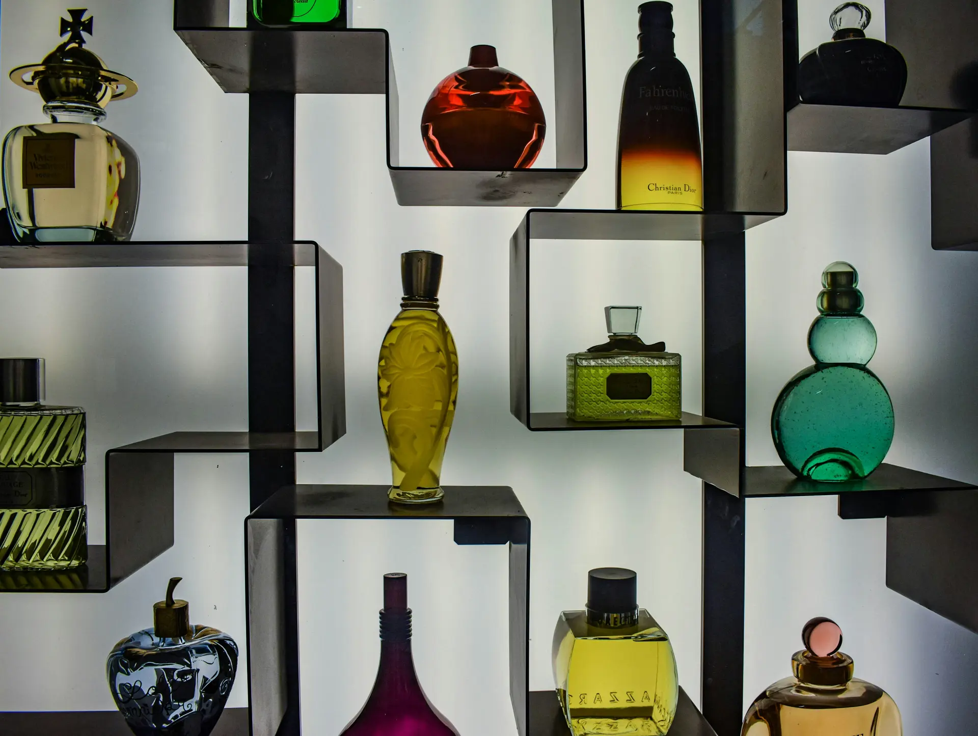 A retail display shelf of colorful perfume bottles